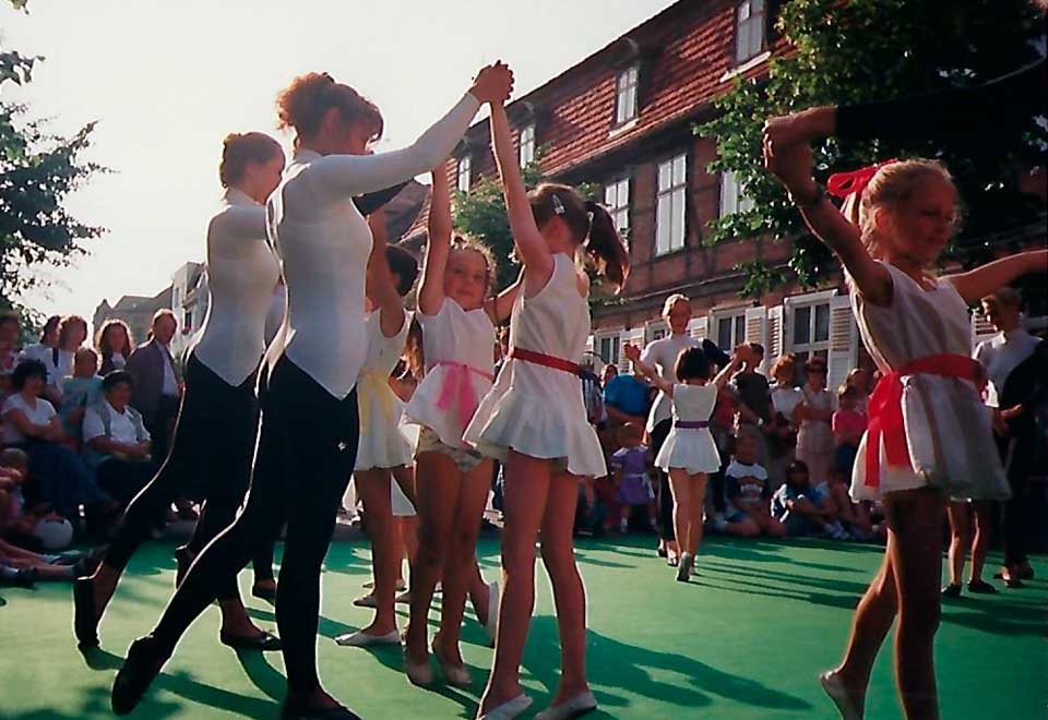 Die großen und kleinen Mädels tanzen zusammen in weißen Kleidern